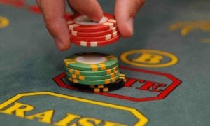 Hand stacking colorful casino chips on a betting table