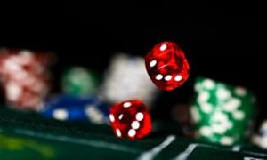 Red dice rolling on a casino table with blurred chips in the background