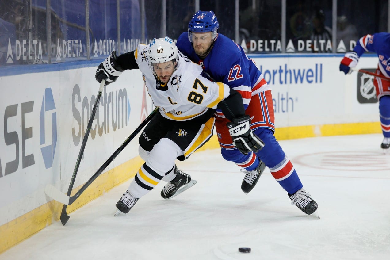 Two hockey players battling for the puck against the boards during an intense game
