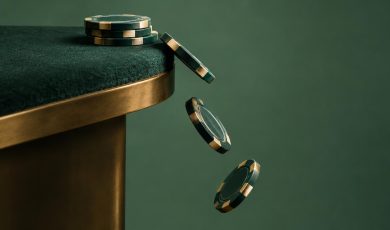 A stack of dark green casino chips sits on a green table edge, with three more chips falling off the side.