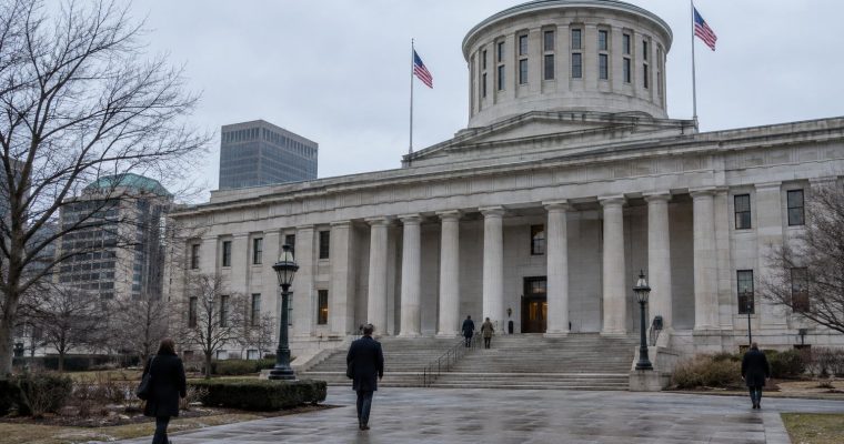 People walk towards the entrance of the Ohio Statehouse in Columbus on a cloudy day.